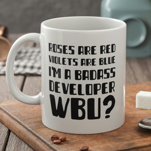 May include: White ceramic mug with black text that reads "Roses are red, Violets are blue, I'm a badass developer, WBU?"