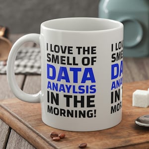 May include: White ceramic coffee mug with black text that reads "I love the smell of data analysis in the morning!" The text "data analysis" is in blue.