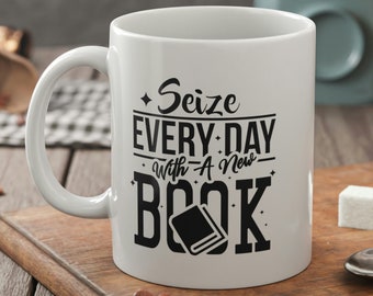 May include: White ceramic mug with a black design that says "Seize Every Day With A New Book" and a black silhouette of a book.