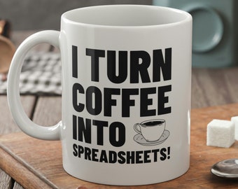 May include: White ceramic coffee mug with black text that reads "I turn coffee into spreadsheets!" with a small black and white illustration of a coffee cup.