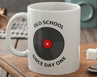 May include: White ceramic mug with a black vinyl record design and the text "Old School Since Day One".