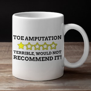 May include: White ceramic coffee mug with a black graphic that says "Toe Amputation" with a one-star rating and the text "Terrible, would not recommend it!"