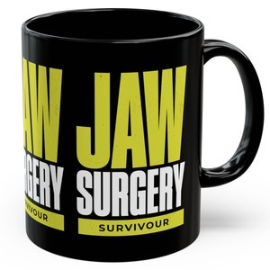 Puede incluir: Taza de cerámica negra con la frase "JAW SURGERY SURVIVOR" en amarillo y blanco. La taza tiene un asa estándar y un acabado brillante, adecuada para bebidas frías o calientes.