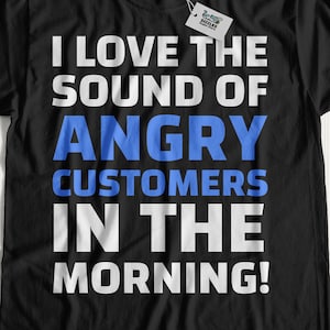 Puede incluir: Camiseta negra con el texto "I LOVE THE SOUND OF ANGRY CUSTOMERS IN THE MORNING!" en letras blancas y azules. La camiseta tiene cuello redondo y mangas cortas. Una etiqueta está sujeta al cuello.