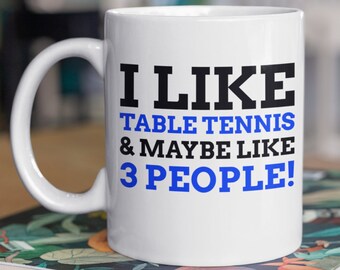 May include: White ceramic mug with a black and blue design. The mug says "I like table tennis & maybe like 3 people!"
