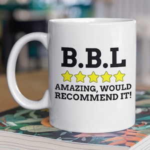 May include: White ceramic mug with a black and yellow design. The mug says "B.B.L.  ***** AMAZING, WOULD RECOMMEND IT!"