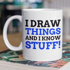Puede incluir: Taza de cerámica blanca con un diseño en negro y azul. La taza dice "I draw things and I know stuff!"