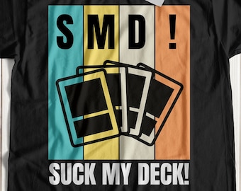 May include: Black t-shirt with a retro-style graphic design. The graphic features a playing card design with the text "SMD!" and "SUCK MY DECK!"