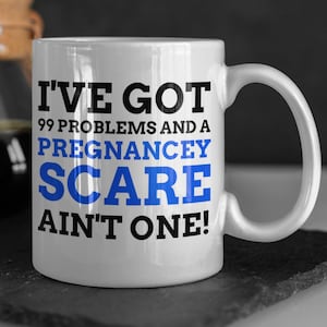 May include: White ceramic mug with black text that reads "I've got 99 problems and a pregnancey scare ain't one!" The text "pregnancey scare" is in blue.