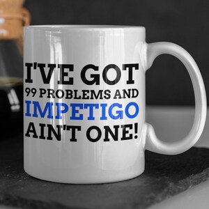 May include: White ceramic mug with a black and blue design. The mug reads "I've got 99 problems and impetigo ain't one!"