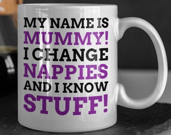 Puede incluir: Taza de cerámica blanca con un diseño en negro y morado. El texto en la taza dice "My name is Mummy! I change nappies and I know stuff!"
