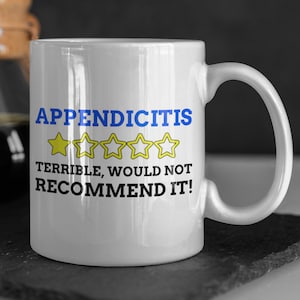 May include: White ceramic coffee mug with a blue and yellow graphic that reads "Appendicitis" with a one-star rating and the text "Terrible, would not recommend it!"