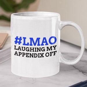 Könnte beinhalten: Weiße Keramik-Kaffeetasse mit einem schwarzen und blauen Design. Die Tasse trägt den Text "#LMAO LAUGHING MY APPENDIX OFF".