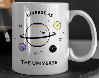 May include: White ceramic mug with a black outline of a planet with a purple, yellow, and white striped design. The planet has a smiling face and is surrounded by stars. The text "DIVERSE AS THE UNIVERSE" is printed on the mug.