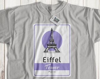 Puede incluir: Camiseta gris con un gráfico de la Torre Eiffel en París. El gráfico está en un rectángulo blanco con un fondo morado y el texto "Eiffel Tower Paris".
