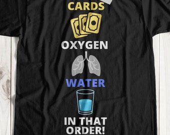 May include: Black t-shirt with the text "CARDS, OXYGEN, WATER, IN THAT ORDER!" in white. The text is accompanied by illustrations of playing cards, lungs, and a glass of water.