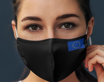 May include: A person wearing a black face mask with the European Union flag printed on the right side. The person is wearing a white t-shirt and has dark hair.