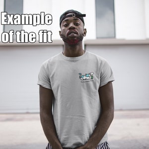 Puede incluir: Una persona lleva una camiseta gris con una ilustraci&oacute;n de dibujos animados de un coche y el texto "Ride or Die" en la parte delantera. La persona lleva una gorra de b&eacute;isbol negra y est&aacute; de pie frente a una puerta de garaje blanca.