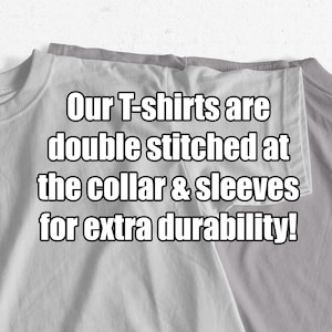 May include: Close-up of two gray t-shirts folded together. The text "Our T-shirts are double stitched at the collar & sleeves for extra durability!" is printed on the shirts.