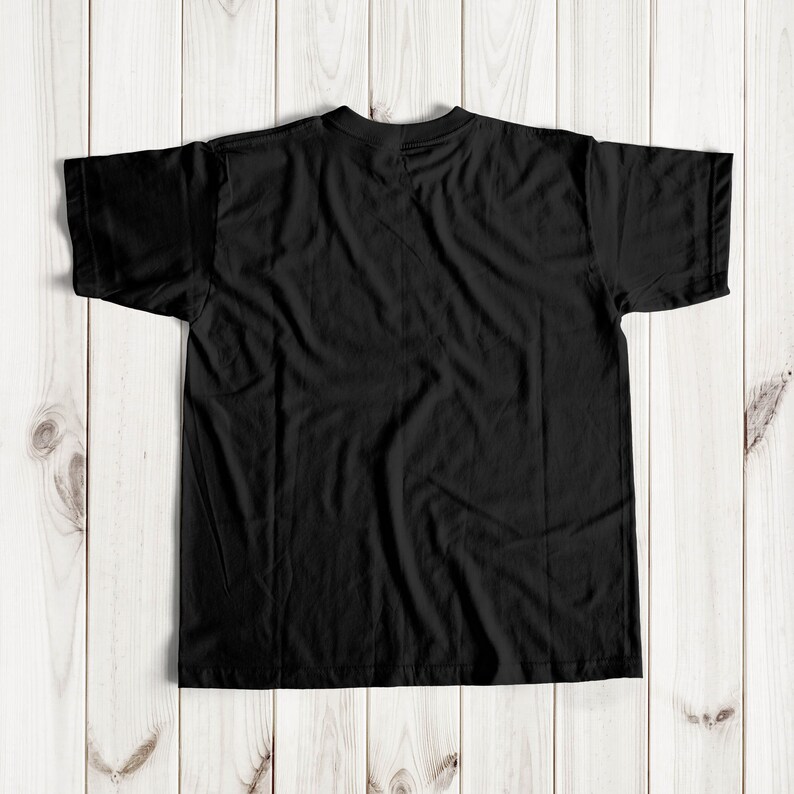 May include: A black t-shirt with short sleeves, laid flat on a wooden surface.