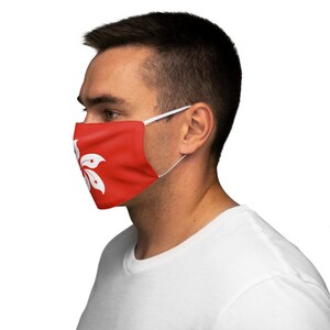 Op de afbeelding: Een persoon draagt ​​een gezichtsmasker met de vlag van Hongkong. Het masker is rood met een witte bauhinia-bloem.