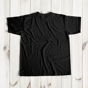 May include: A black t-shirt with short sleeves, laid flat on a wooden surface.
