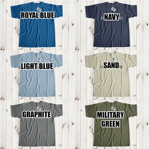 May include: A collage of 12 t-shirts in various colors, including yellow, royal blue, navy, white, black, light blue, sand, light pink/coral, ash/grey, graphite, military green, and red. Each t-shirt has a different color and is displayed on a white wooden background.