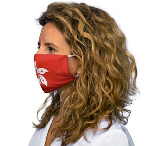 Op de afbeelding: Een vrouw draagt ​​een rood gezichtsmasker met een wit Hong Kong-vlagontwerp. Het masker heeft witte elastische banden.