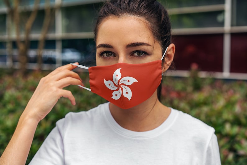 Op de afbeelding: Een vrouw draagt ​​een rood gezichtsmasker met de vlag van Hongkong erop gedrukt. Het masker heeft een wit bauhinia-bloemmotief.
