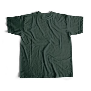 May include: A dark green t-shirt, laid flat on a white surface. The shirt has short sleeves and a crew neck. The fabric appears to be cotton or a similar material, with visible texture and slight wrinkles. The overall look is casual and simple.
