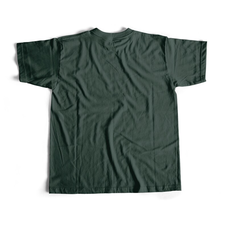 May include: A dark green t-shirt, laid flat on a white surface. The shirt has short sleeves and a crew neck. The fabric appears to be cotton or a similar material, with visible texture and slight wrinkles. The overall look is casual and simple.
