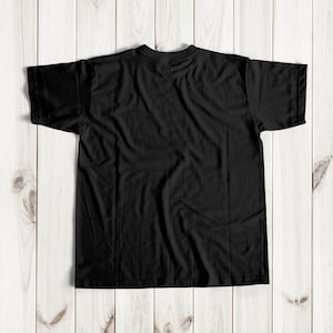 Puede incluir: Una camiseta negra de manga corta, puesta plana sobre una superficie de madera.