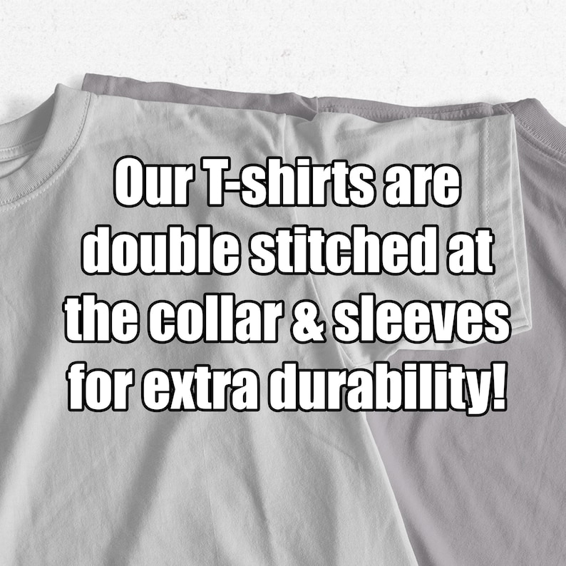 Puede incluir: Primer plano de dos camisetas grises dobladas juntas. El texto "Our T-shirts are double stitched at the collar & sleeves for extra durability!" est&aacute; impreso en las camisetas.