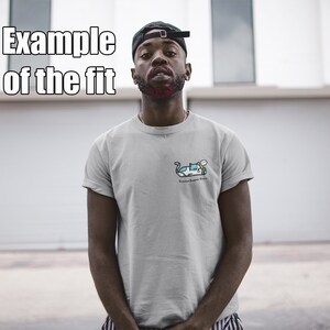 May include: A person wearing a grey t-shirt with a cartoon illustration of a car and the text "Ride or Die" on the front. The person is wearing a black baseball cap and standing in front of a white garage door.
