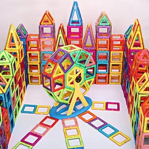 May include: A vibrant magnetic building block set. The set features squares, triangles, and rectangles in bright colours including red, yellow, blue, and green. The blocks are arranged to resemble a castle with a Ferris wheel.