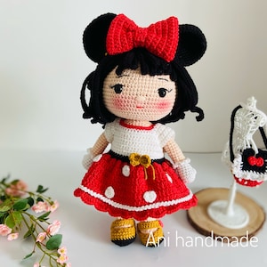 May include: Crocheted doll with black hair, red and white polka dot dress, and a red bow. The doll is wearing yellow shoes and has a white crocheted purse with a red bow.