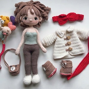 以下が含まれることがあります： 茶色の髪の毛をした手作りのかぎ針編みの人形。青と白のトップスと茶色のズボンを着ています。白いコート、赤いスカーフ、ブーツ、ハンドバッグなどのマッチング衣装が付属しています。かぎ針編みの風船のブーケと赤いリボンも含まれています。
