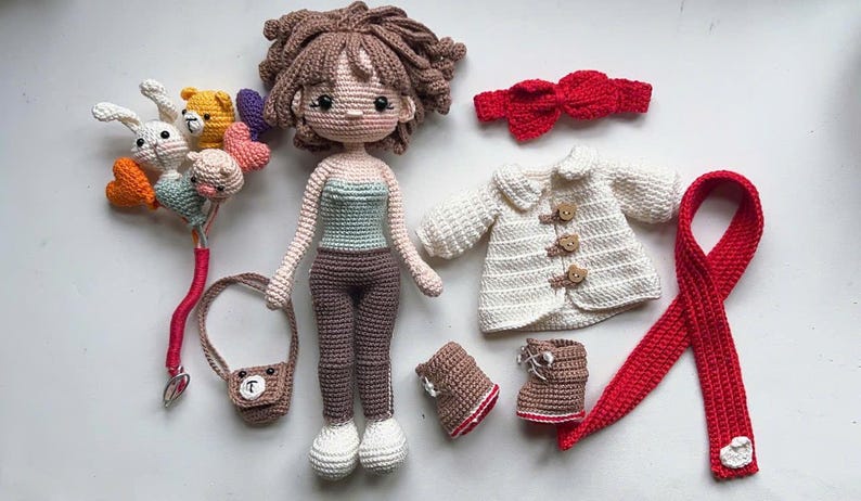 以下が含まれることがあります： 茶色の髪の毛をした手作りのかぎ針編みの人形。青と白のトップスと茶色のズボンを着ています。白いコート、赤いスカーフ、ブーツ、ハンドバッグなどのマッチング衣装が付属しています。かぎ針編みの風船のブーケと赤いリボンも含まれています。