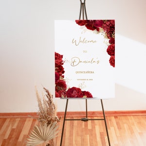 Puede incluir: Un cartel de bienvenida para el Quincea&ntilde;era de Daniela con un dise&ntilde;o floral rojo y dorado. El cartel dice "Bienvenido al Quincea&ntilde;era de Daniela" con la fecha "20 de noviembre de 20XX".