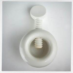 May include: A white nutcracker with a circular body and a screw mechanism. The nutcracker has a round handle and a threaded screw for cracking nuts. The design is simple and modern, with a focus on functionality.