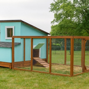 Puede incluir: Un gallinero turquesa y marrón con un cerramiento de malla metálica. El gallinero tiene una pequeña ventana y una rampa que conduce al interior. La estructura está sobre un césped.