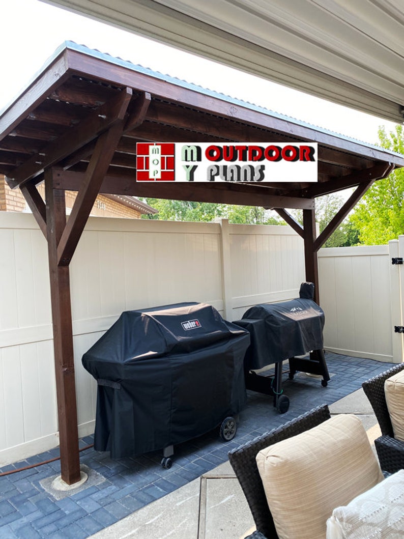 May include: A wooden pergola with a dark brown stain and a corrugated metal roof. Two black grill covers are visible beneath the pergola. The text "M Outdoor Plans" is displayed on a white background.