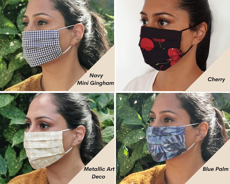 Op de afbeelding: Vier verschillende gezichtsmaskers met verschillende patronen. De maskers zijn geplooid en hebben elastische oorlussen. De patronen omvatten marineblauw mini-gingham, kersenprint, metallic art deco en blauwe palm.