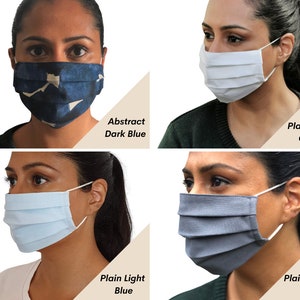 Op de afbeelding: Vier verschillende gezichtsmaskers, elk gedragen door een persoon. De maskers zijn: abstract donkerblauw, effen wit katoen, effen lichtblauw en effen schoolgrijs.