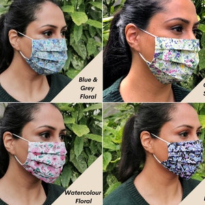 Op de afbeelding: Vier verschillende gepatroneerde gezichtsmaskers, elk gedragen door een persoon. De maskers zijn gemaakt van stof en hebben een geplisseerd ontwerp. De patronen zijn: blauw en grijs bloemen, tuinsc&egrave;ne, aquarel bloemen en blauwe en lila bloemen.