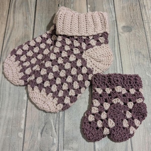 May include: A pair of handmade crochet slippers and a matching cuff in a granny square pattern. The slippers and cuff are in shades of purple and beige. The slippers have a folded-over cuff.