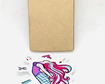 May include: A blank wooden sign with a mermaid sticker attached. The sticker features a mermaid with pink and blue hair, a purple top, and a blue tail. The text "Sweet Crafting Mermaid" is written below the mermaid.
