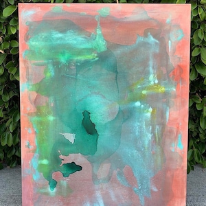 May include: Abstract painting on canvas with a blend of colors. The artwork features a reddish-brown background with overlapping areas of green and blue hues. The paint appears to have a watercolor effect, with soft edges and color gradients.