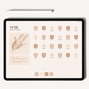 Op de afbeelding: Een digitaal tabletscherm met een beige achtergrond en een raster van app-pictogrammen. De pictogrammen zijn wit omrand en hebben een minimalistisch ontwerp. De tekst "think progress not perfection" wordt op het scherm weergegeven.