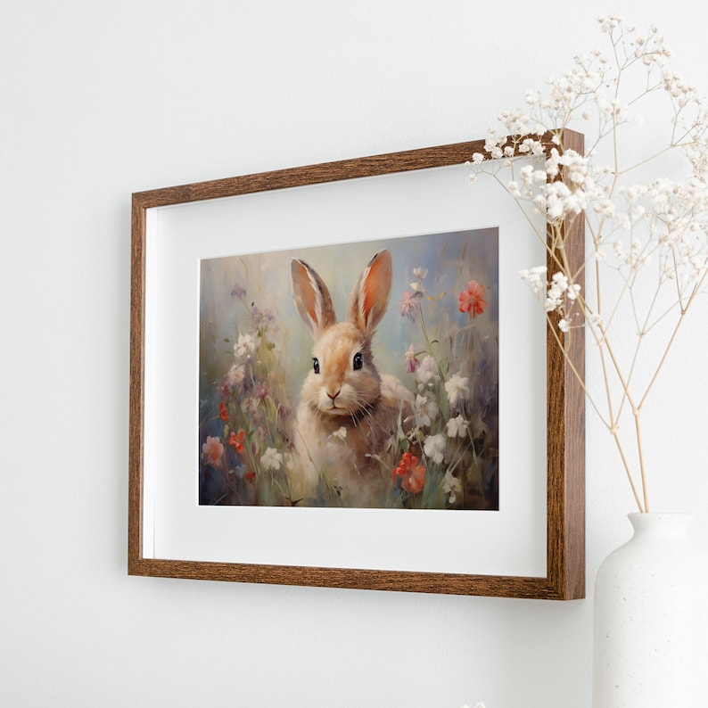 May include: A framed painting of a brown rabbit sitting in a field of white and red flowers. The rabbit has brown eyes and a white nose. The background is a soft blue.